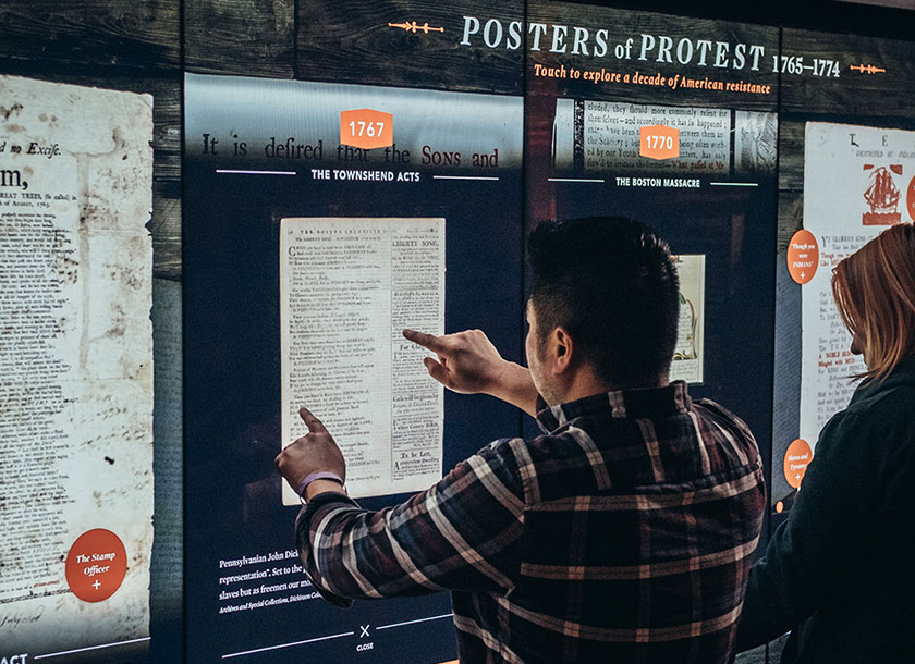 Visitors interacting with a touch video wall at the Museum of the American Revolution.