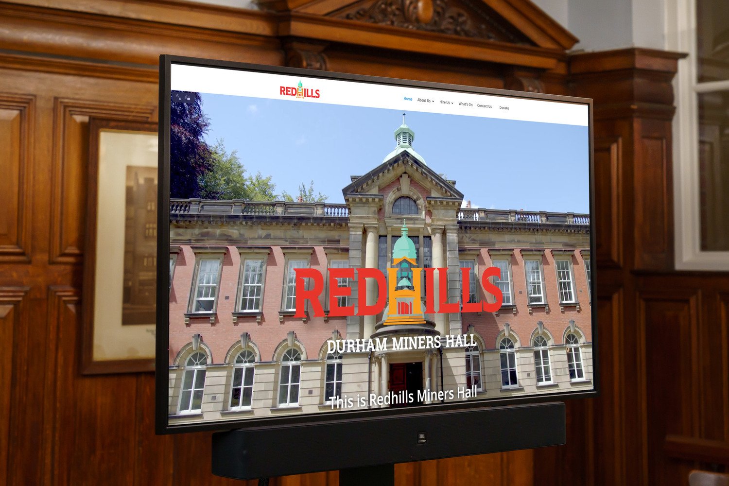 A screen on a Mobile trolley that has the Redhills website on it.