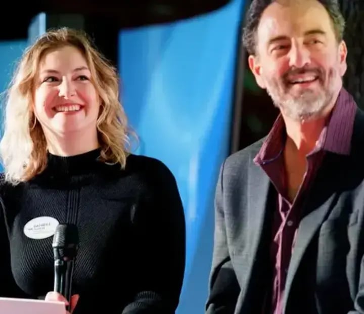 A man and woman stand side by side at a podium, engaged in a thought leadership discussion or presentation.