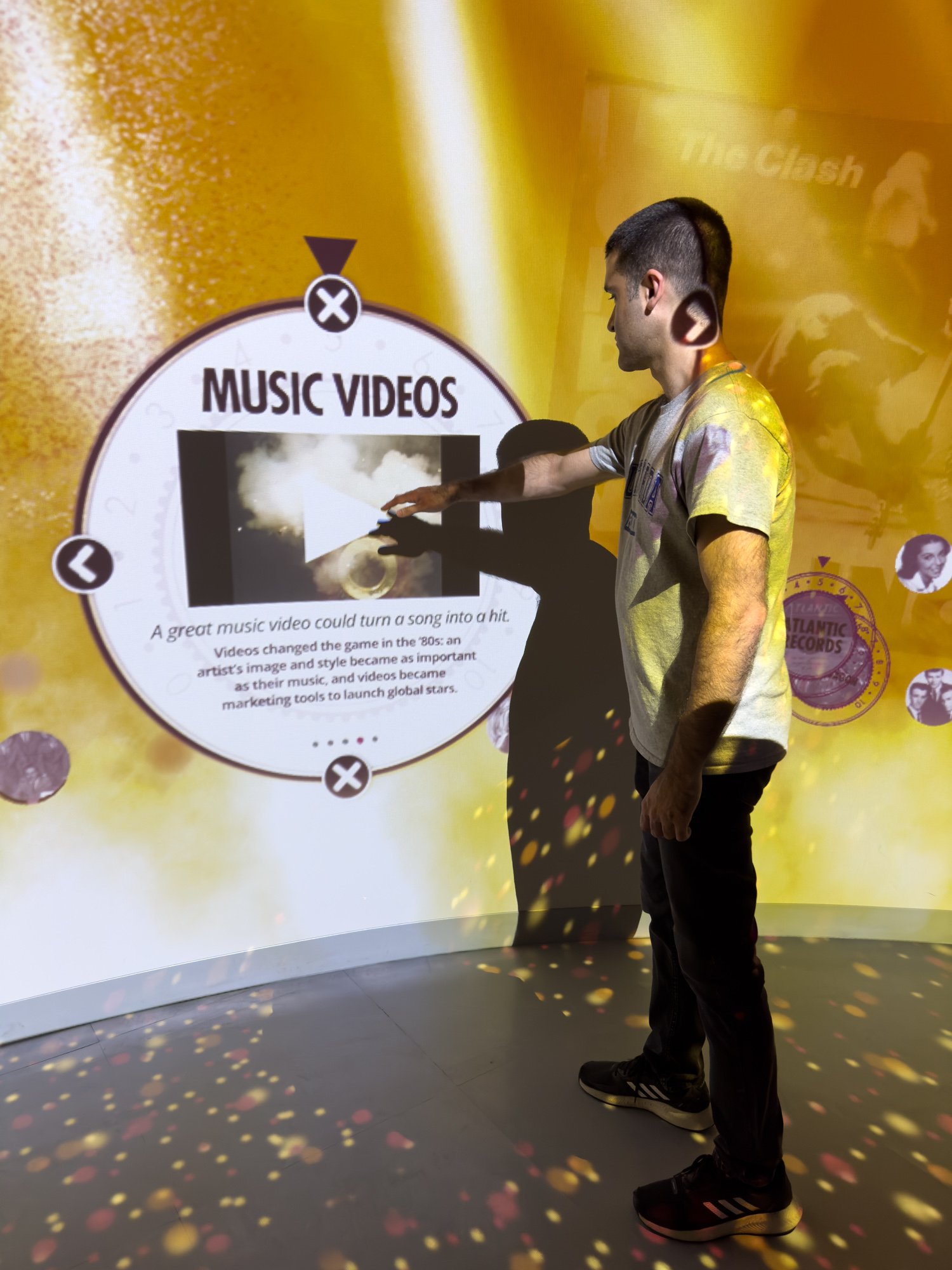 A man interacting with the media on a wall learning more about music videos.