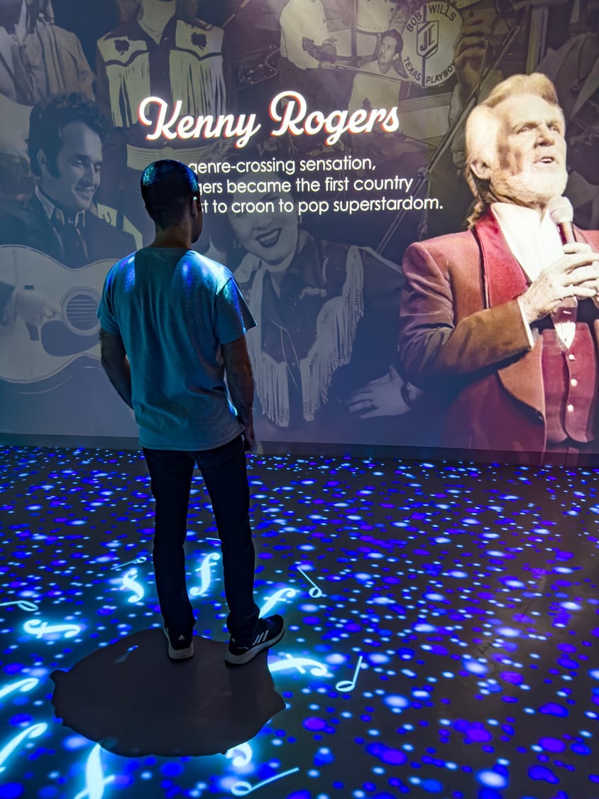 A person looking at Kenny Rogers history on the curved media projection wall.