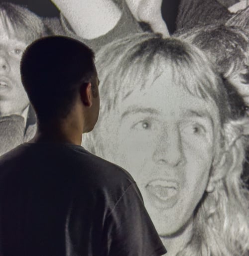 A man looking at a wall that has music legends on it.