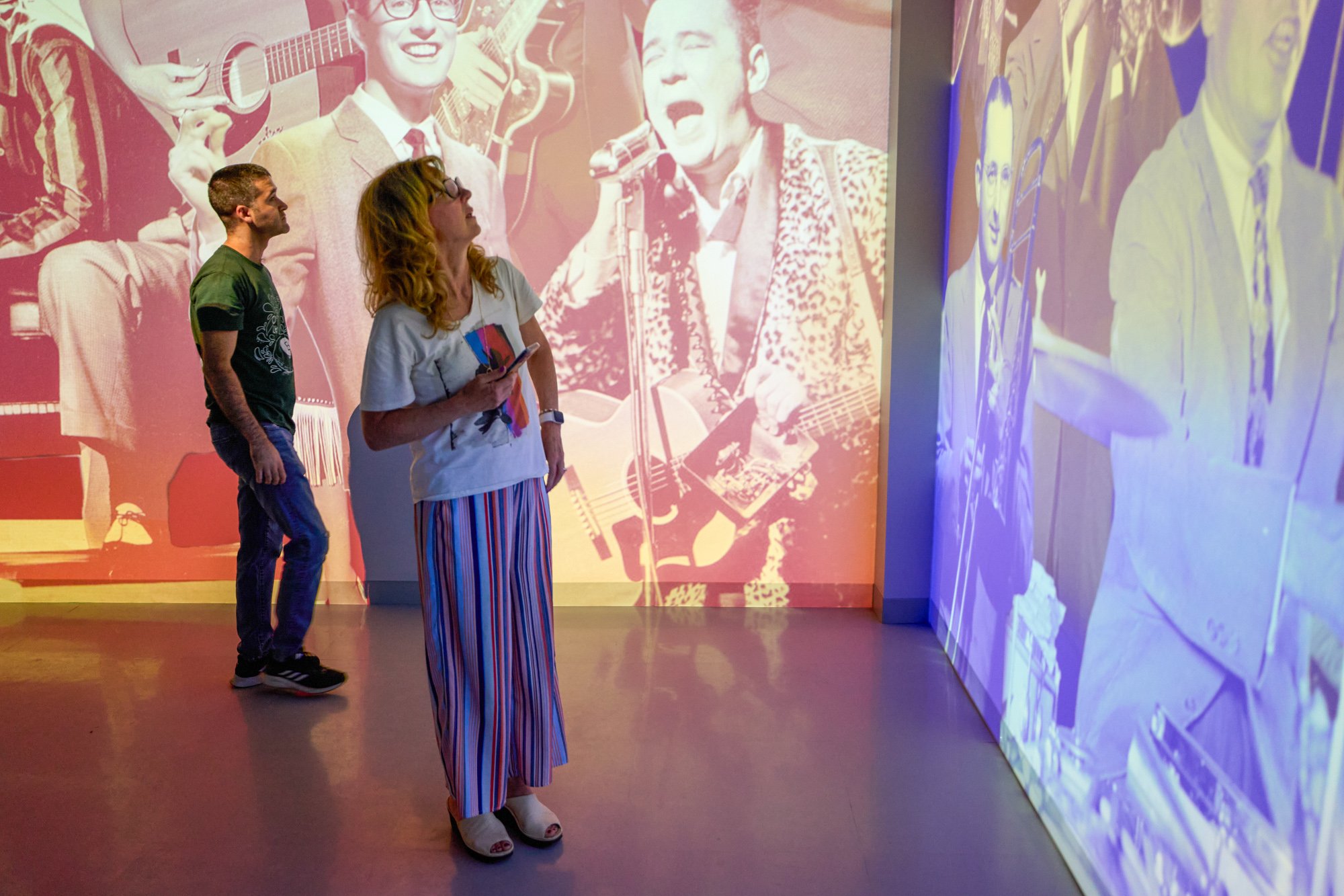 Two people looking at the media on a wall.