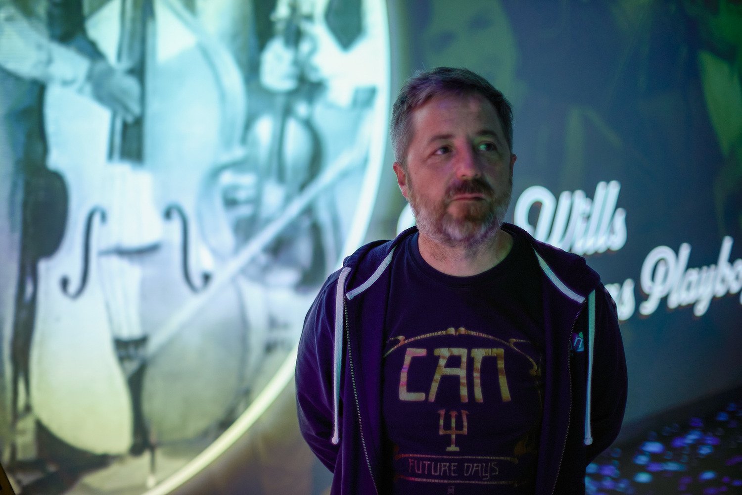 A man looking around the room and listening to the audio about music legends.