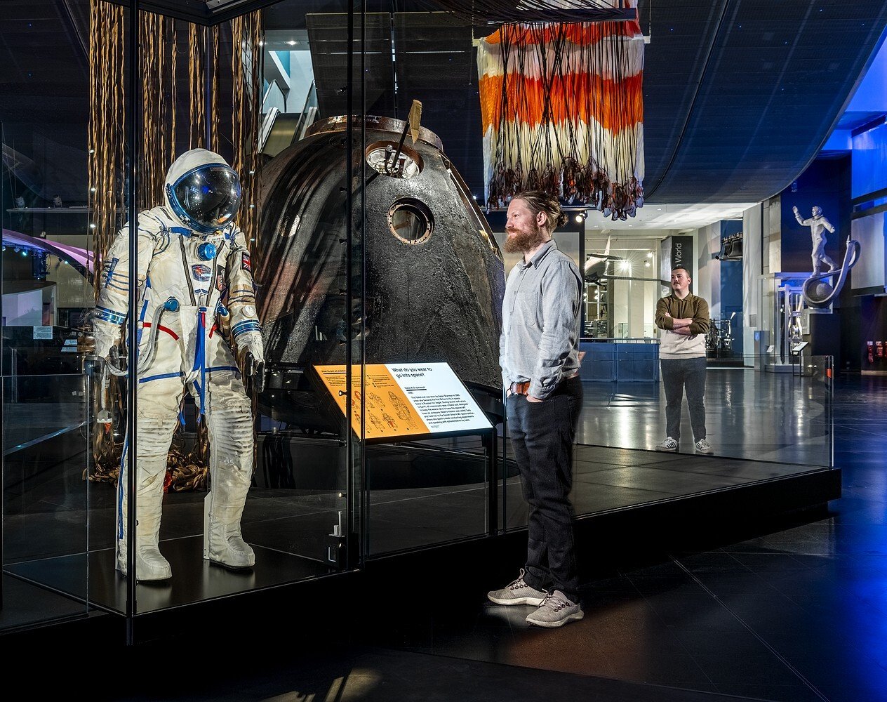 A man looking at a space suit exhibit.