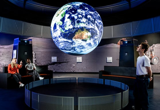Group of people staring at floating Earth.