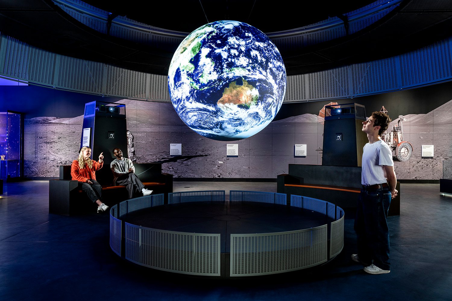 People looking at a floating sphere displaying the earth.