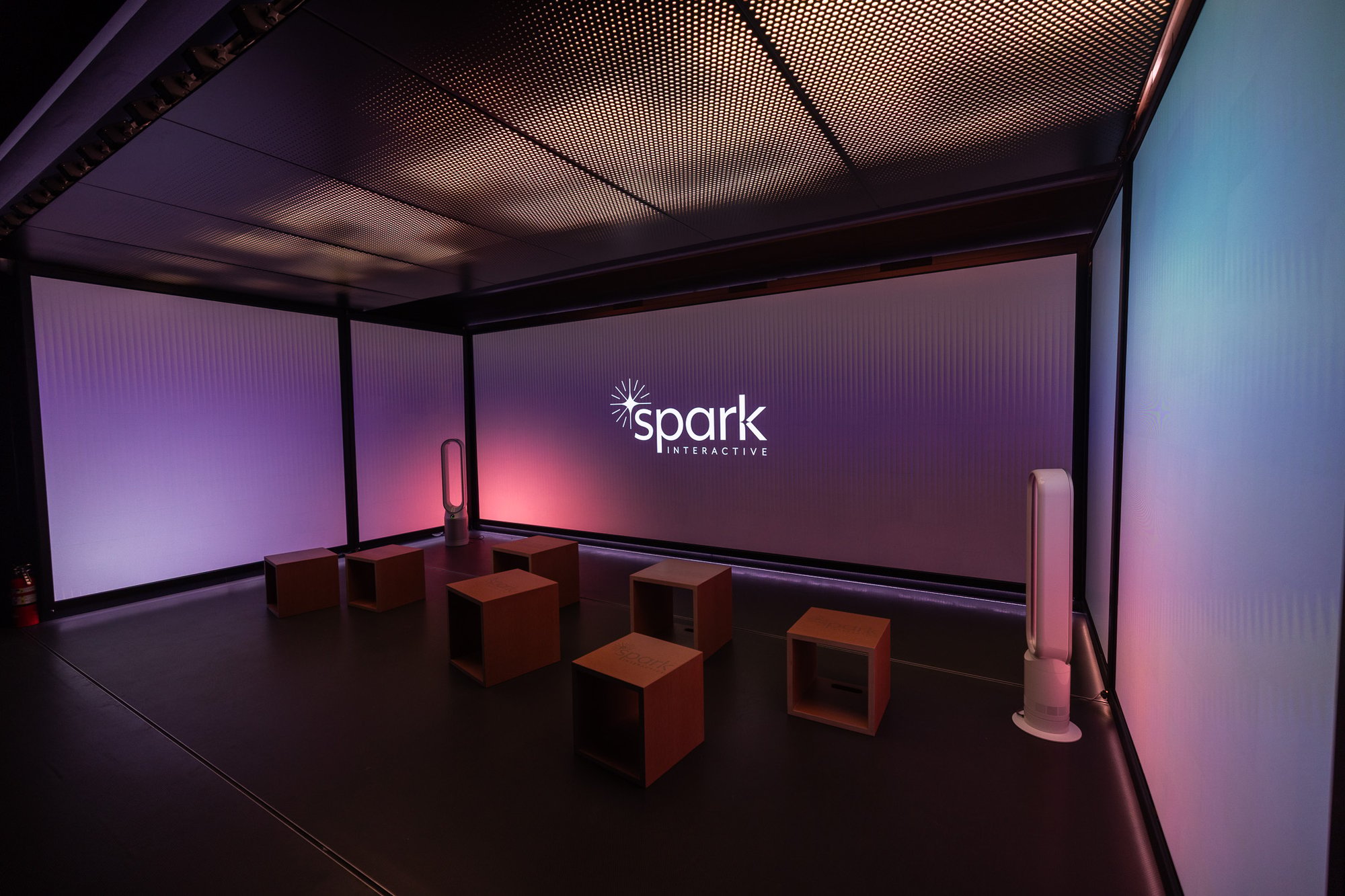 Multiple LED walls in a space with wooden sit panels and the 'Spark Interactive' brand.