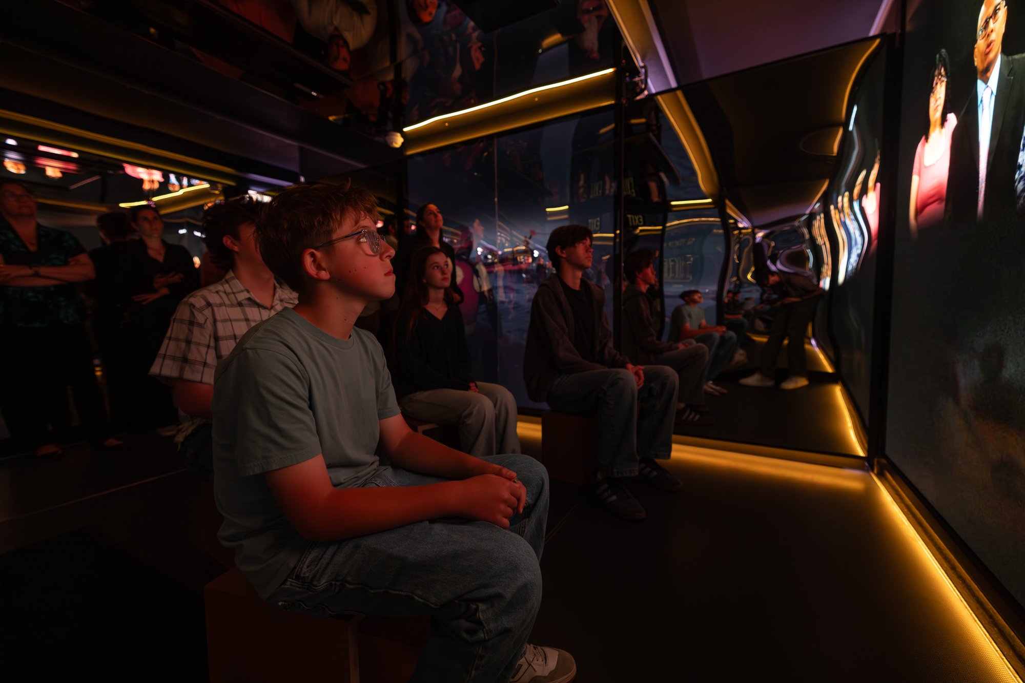 Group of people sitting and looking up at media.