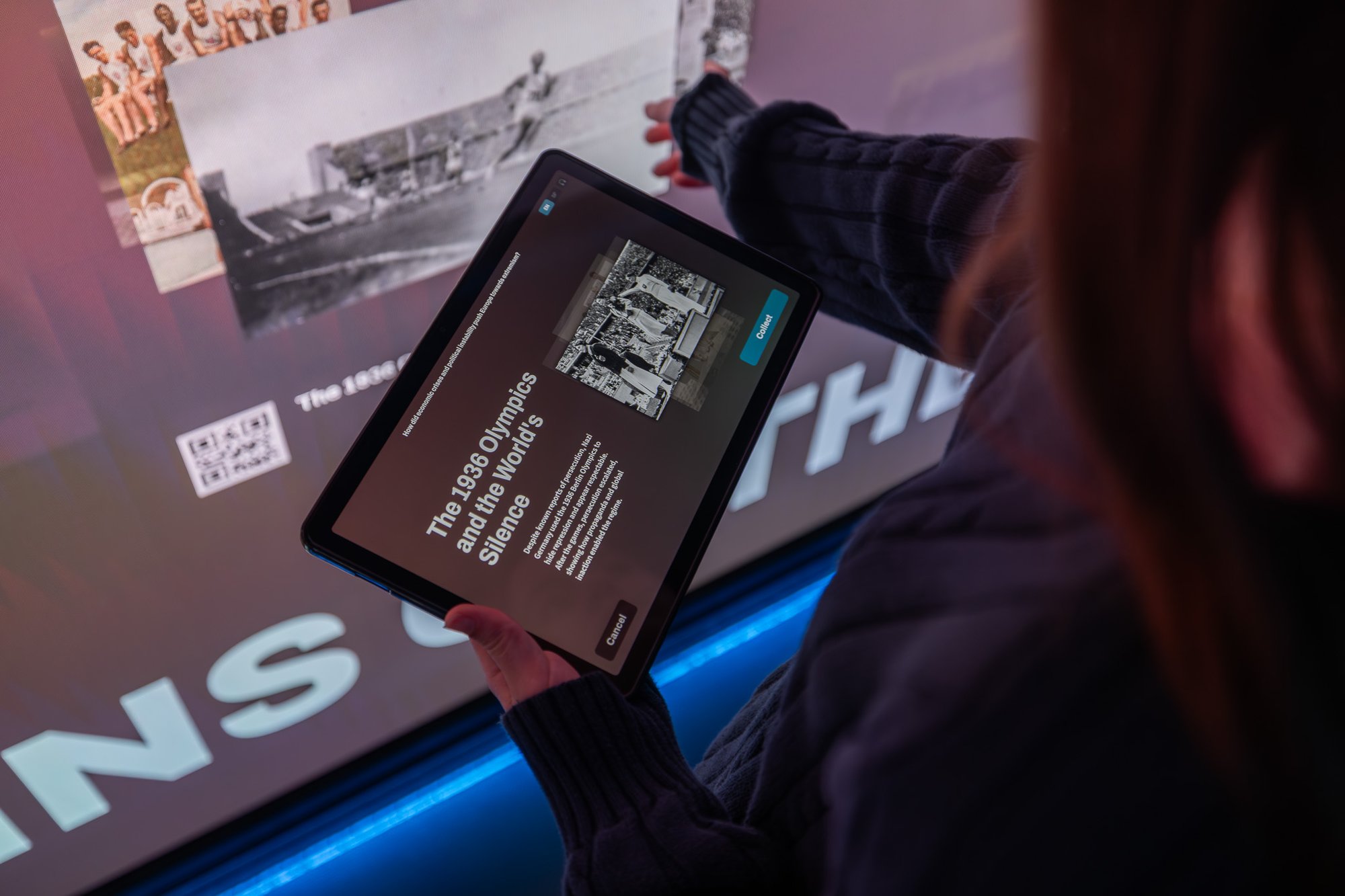 Kid holding tablet while interacting with touchscreen.