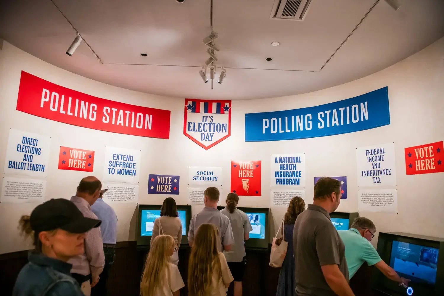 Crowd of people interacting with the polling station exhibit.