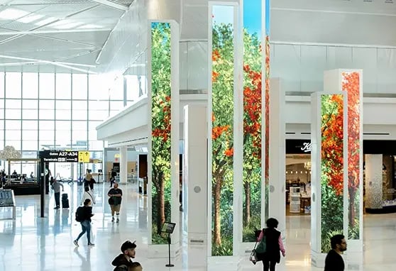 Tall, high-resolution LED columns display dynamic visuals for travelers in the terminal.