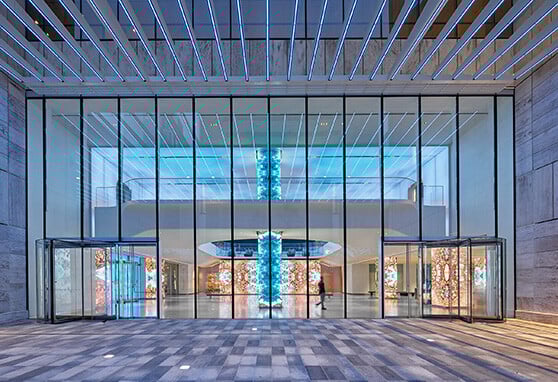 The glass façade of this modern lobby reveals a stunning, immersive LED installation with vibrant digital art and blue-lit ceilings, creating a futuristic and welcoming entrance experience.