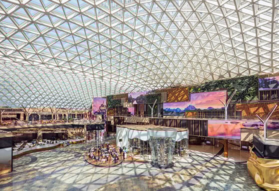 The stunning atrium at MGM COTAI bathed in natural light featuring immersive digital displays and elegant dining, blending architecture and technology in a grand public space.
