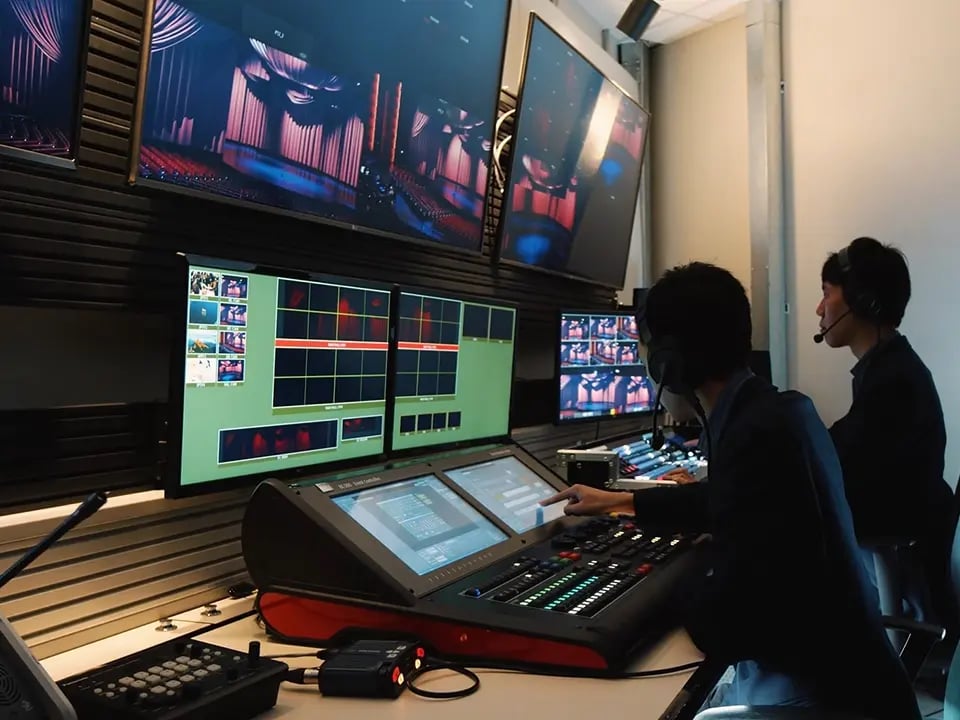 Two AV technicians controlling a large scale AV deployment from a centralized control room.