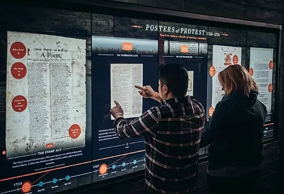 Two guests to the Museum of the American Revolution interacting with a touchscreen to learn more about the documents and literature that fueled the American Revolution.