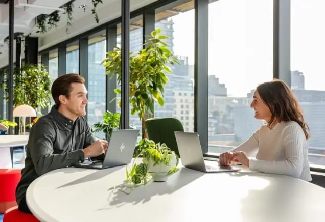 Two professionals having a conversation within a workspace.