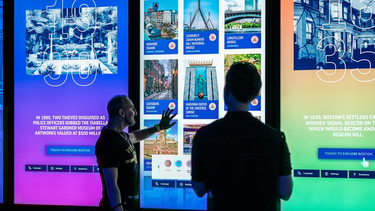 Two visitors to View Boston interacting with a touch screen.