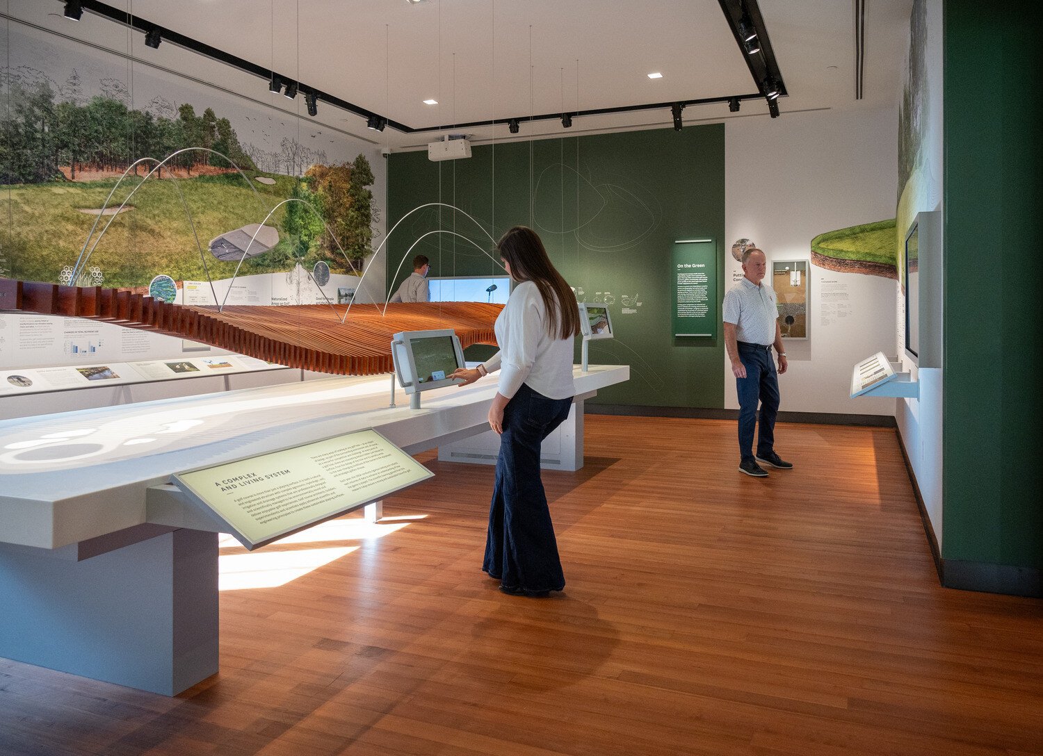 Women using the golf touch table with man looking at the walls