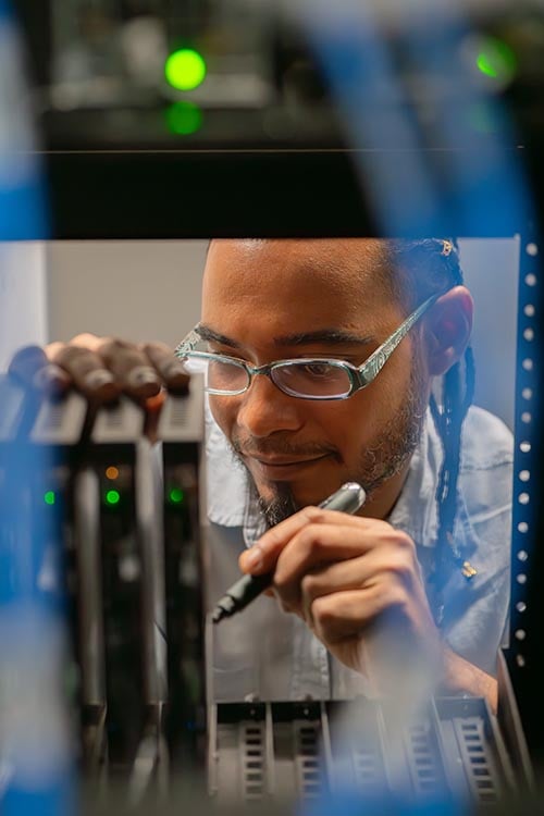 Electrosonic employee working on the components within an AV rack. 