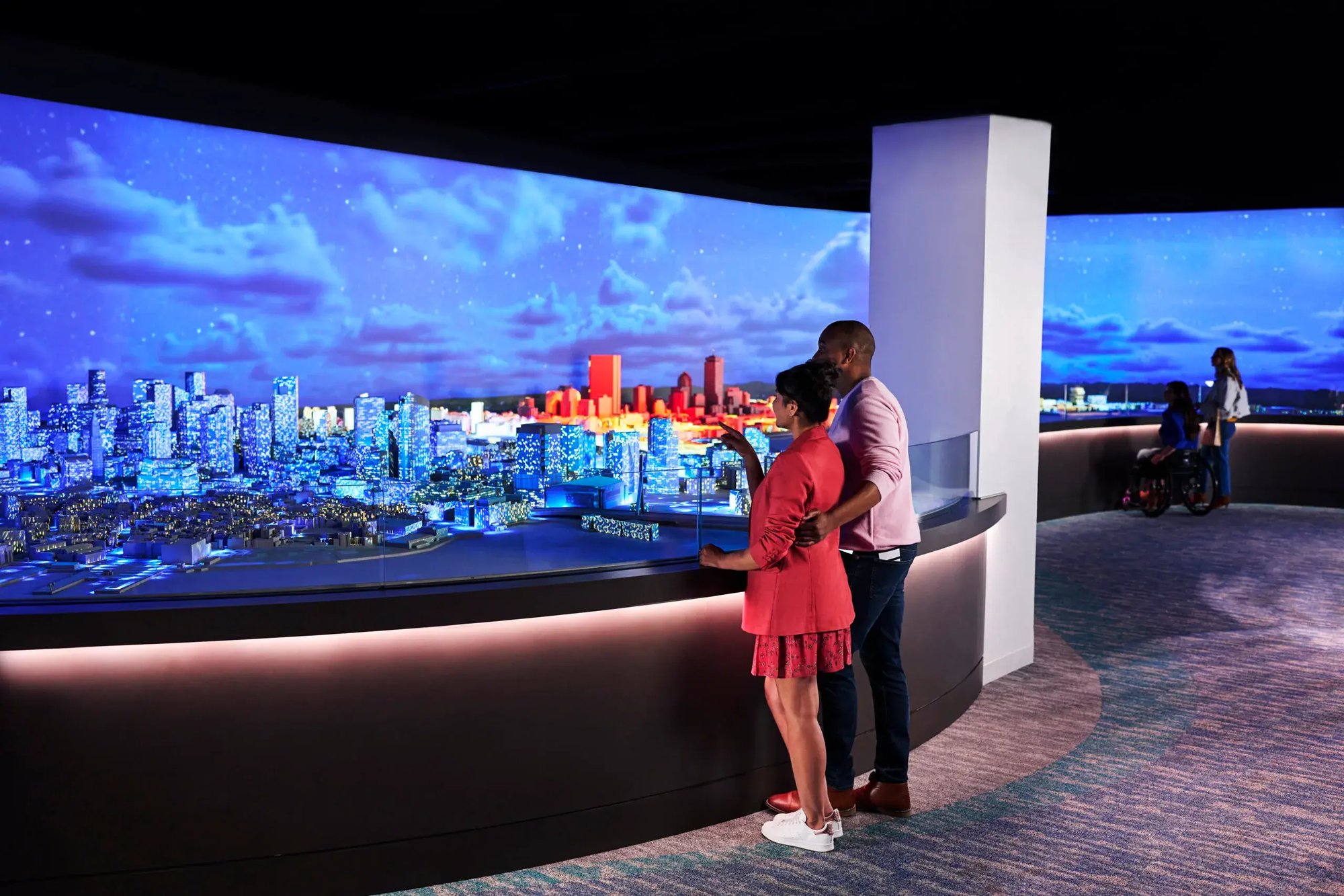 Two visitors looking at the projection mapping solution on a miniature Boston.
