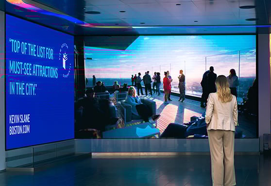 Visitors of View Boston watches an immersive digital wall showcasing panoramic rooftop views at View Boston, a top-rated city attraction.