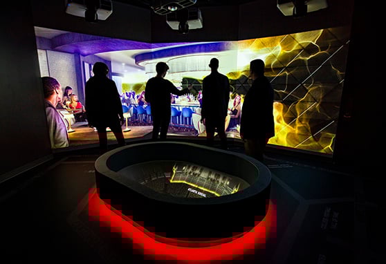 Visitors stand in a dark, immersive exhibit room at the Atlanta Hawks Sales Center.