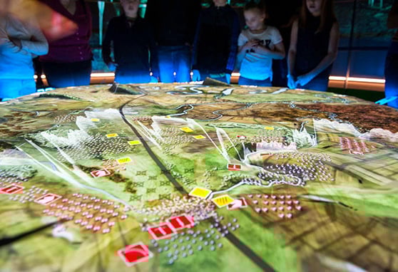 Visitors to Battle of Bannockburn Visitor Centre in Stirling, Scotland surround a projected recreation of the battlefield.
