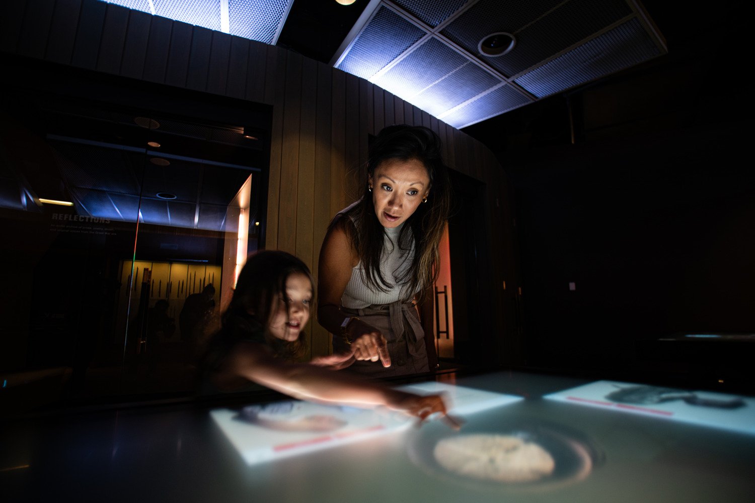 A woman and a child interacting with a touch table.