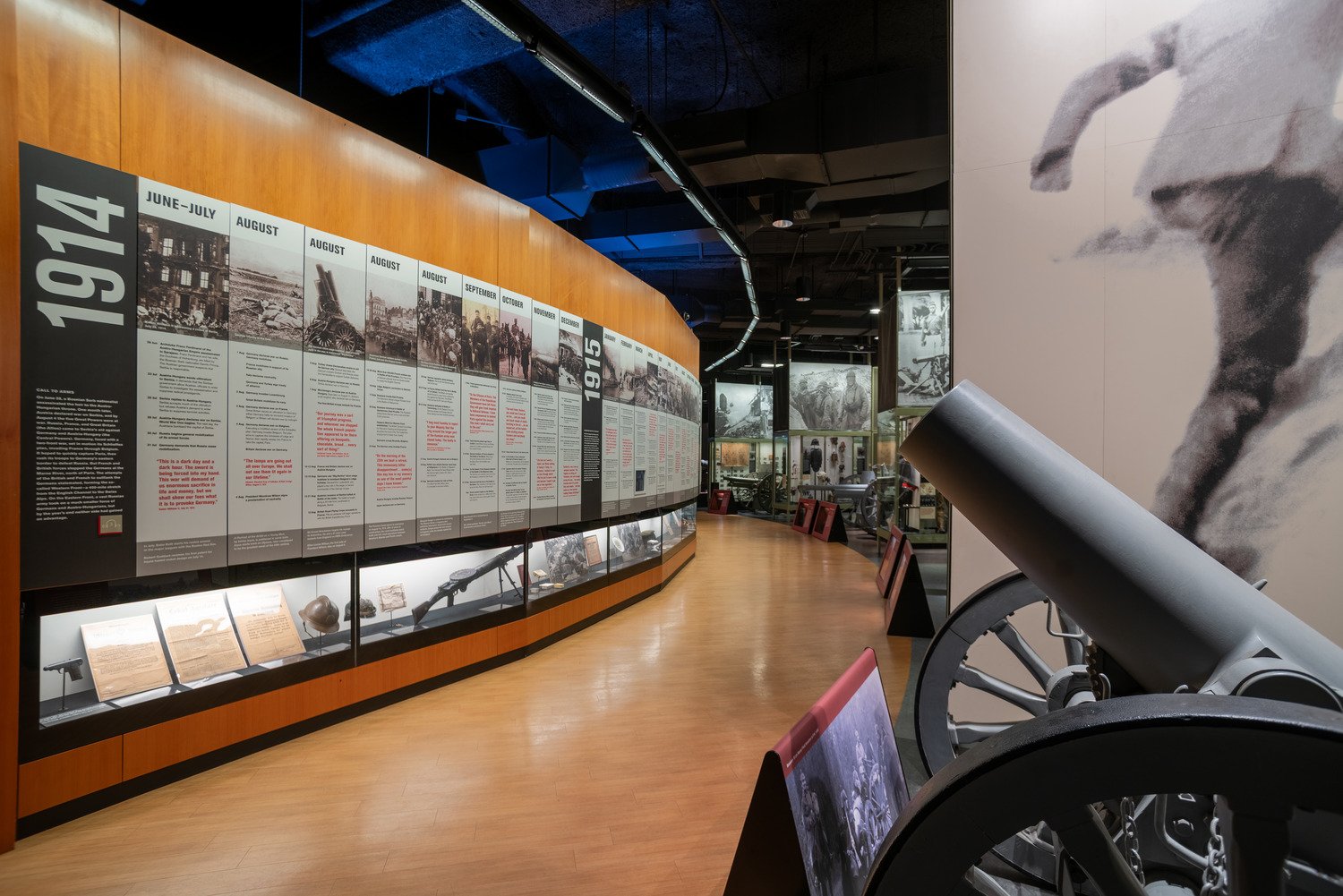 A cannon with a wall that has historical events and memorabilia.