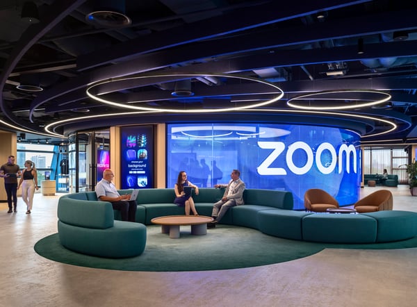 A room with people talking on couches in front of a Zoom wall